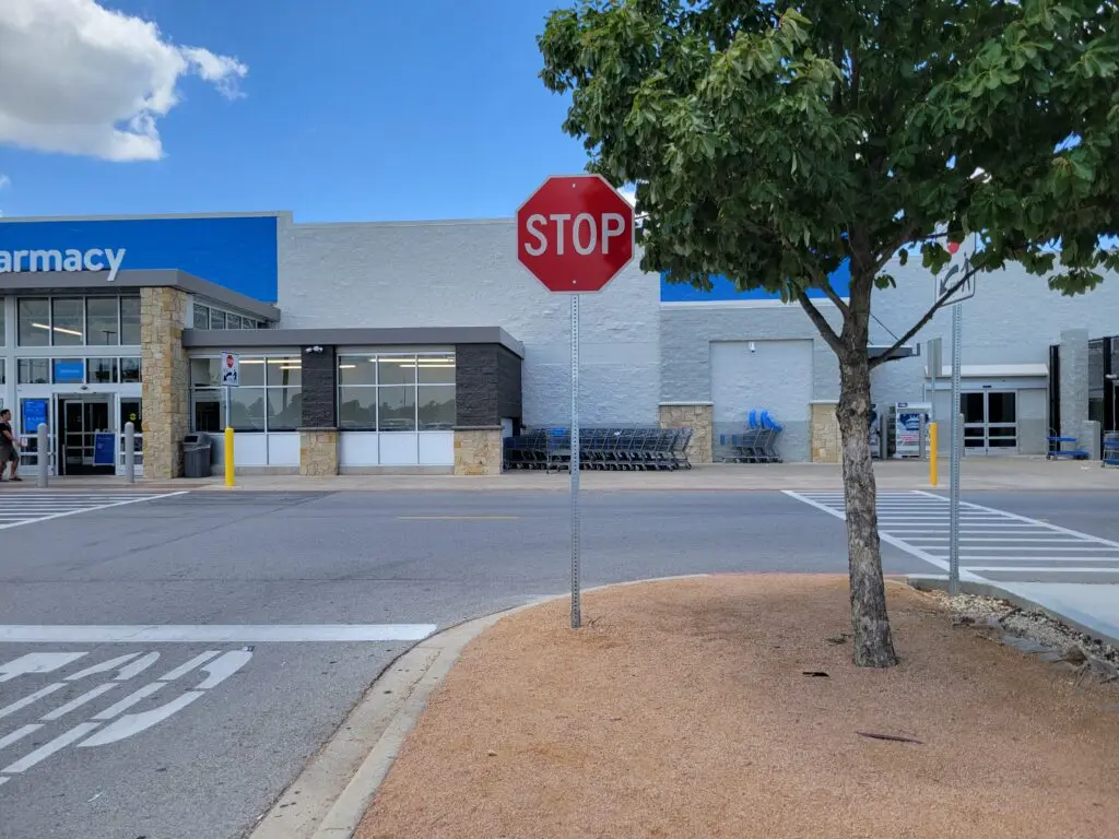 A bare ugly metal sign pole in a commercial parking lot.