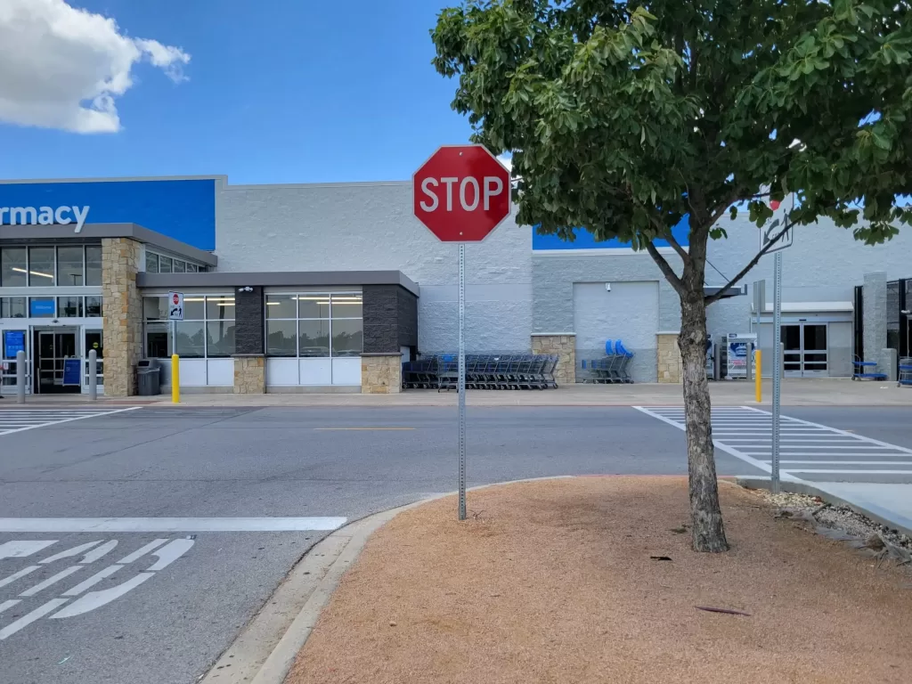 A bare ugly metal sign pole in a commercial parking lot.